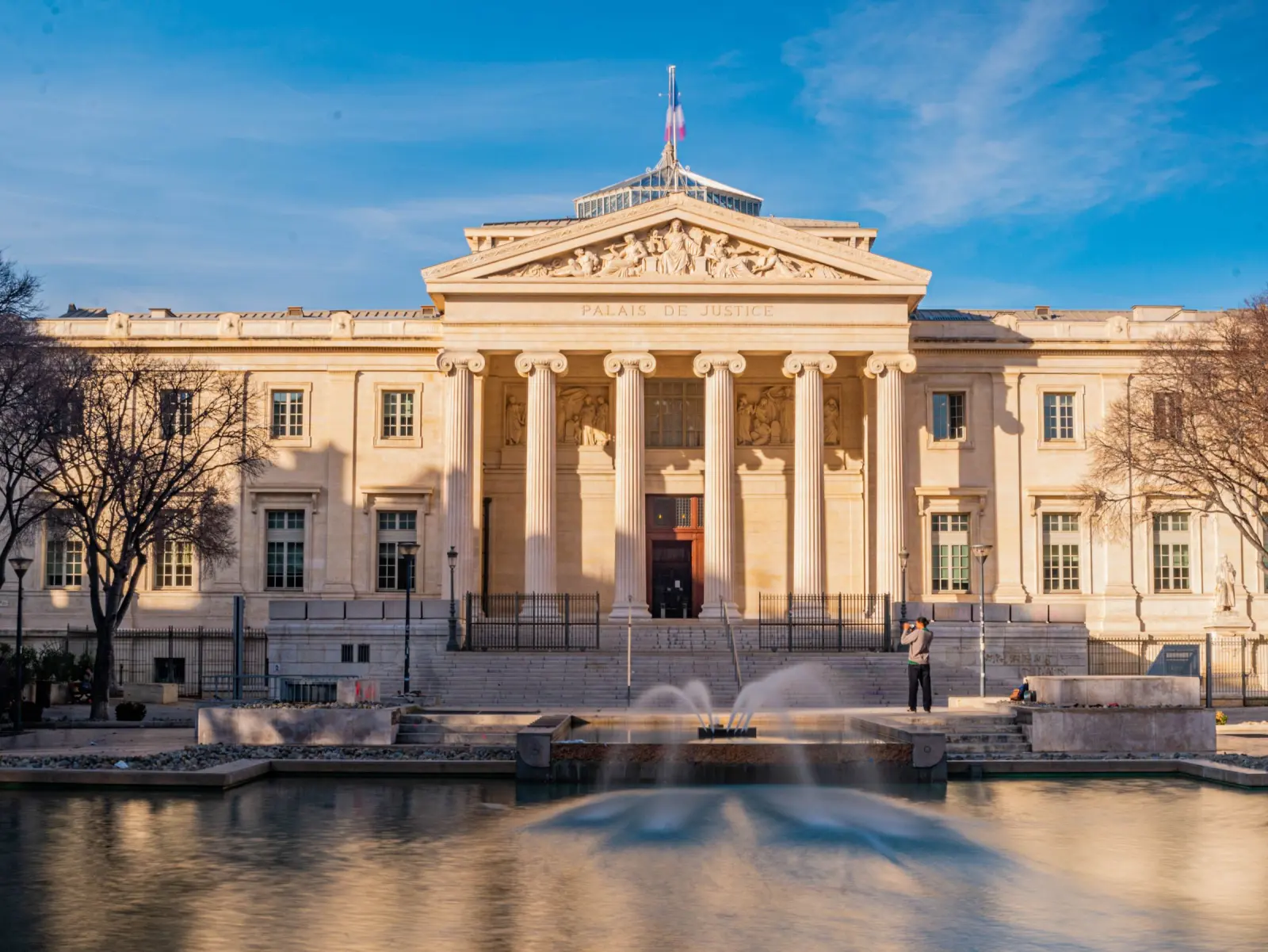 The neoclassical facade of a courthouse across a pool of water.